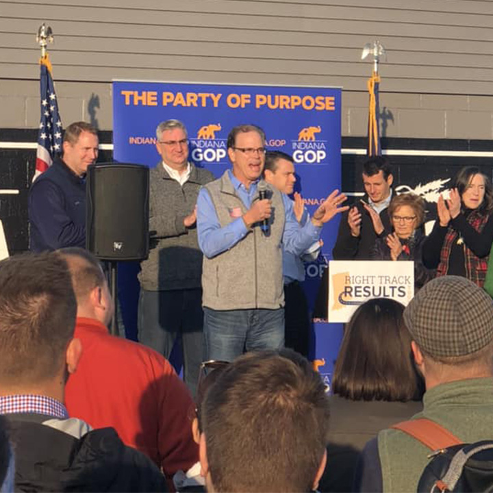 Governor Mike Braun addresses a crowd, holding a microphone
