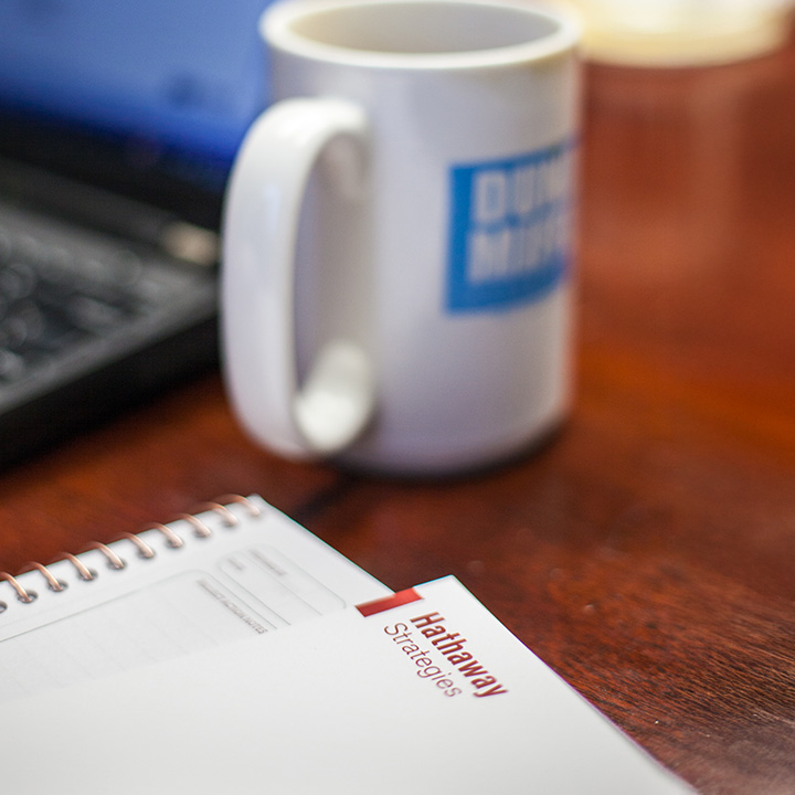 A pad of paper with Hathaway Strategies letterhead; a mug and laptop are out of focus in the background